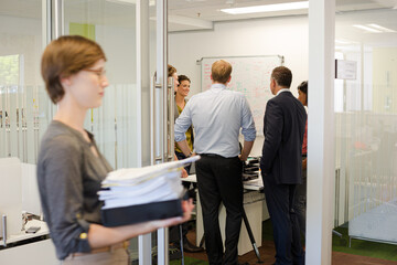 Businesswoman carrying pile of documents in office