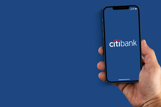 Male hand holding a smartphone with Citibank App on the screen. Blue background. Rio de Janeiro, RJ, Brazil. August 2021.