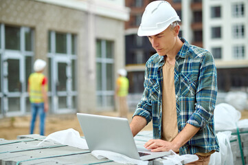Focused professional male engineer using his laptop outdoors