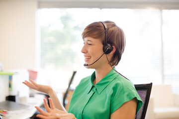 Businesswoman talking on headset at desk