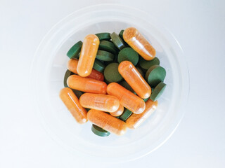 orange and green pills on white background
