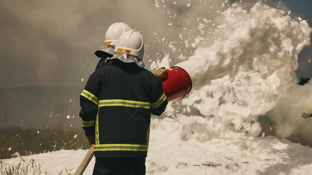 Firemen extinguishing fire in field