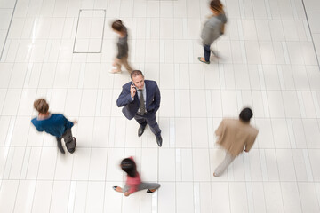 Businessman smiling in busy office hallway