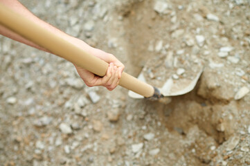 Hand of an experienced builder digging ground using a spade