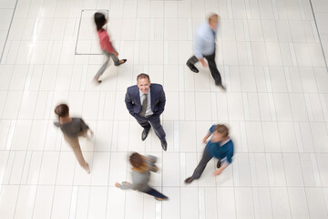 Businessman smiling in busy office hallway