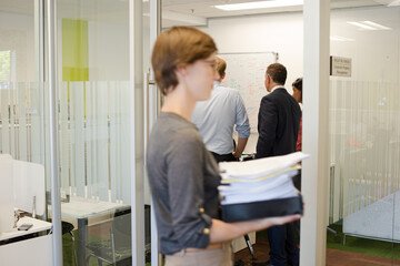 Obraz premium Businesswoman carrying pile of documents in office