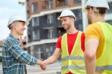 Handsome bearded Caucasian construction worker shaking his colleague hand