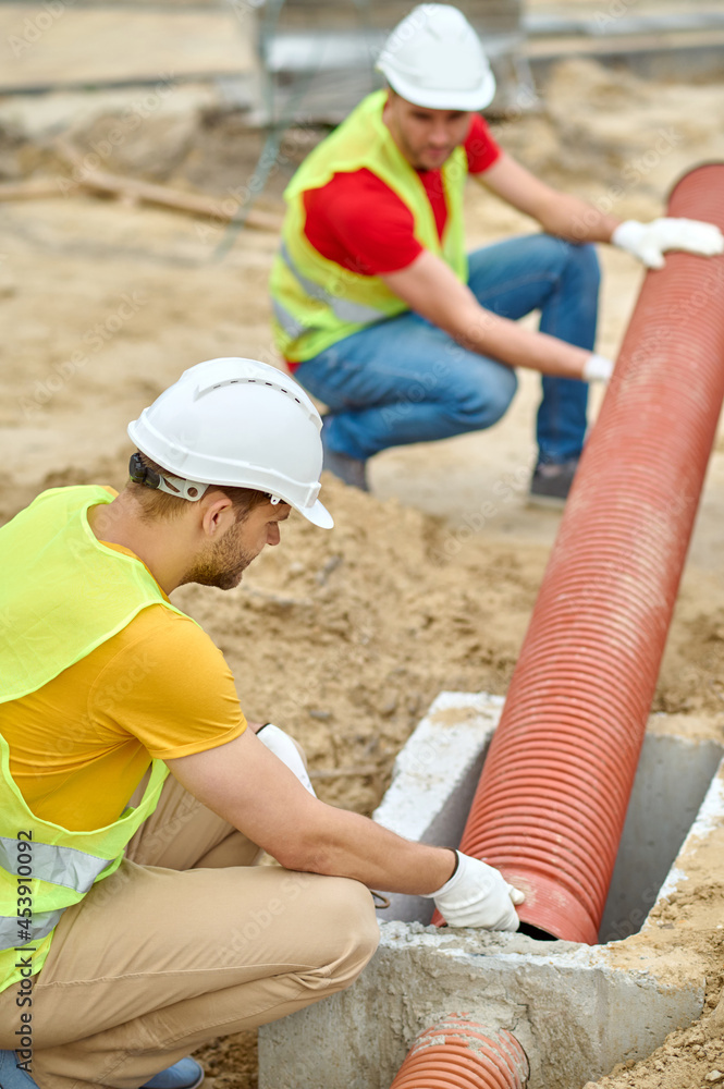 Poster Two experienced workers installing a residential sewer line