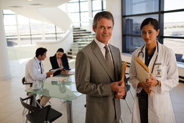 Fototapeta premium Doctor and businessman handshaking in hospital lobby