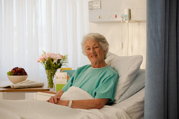 Portrait of smiling aging patient in hospital bed