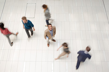 Businessman smiling in busy office hallway