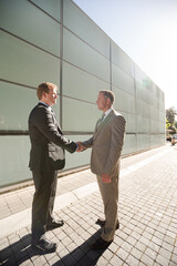 Businessmen shaking hands on city street