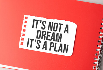 The word It's not a dream, it's a plan on torn paper on red notepad,.