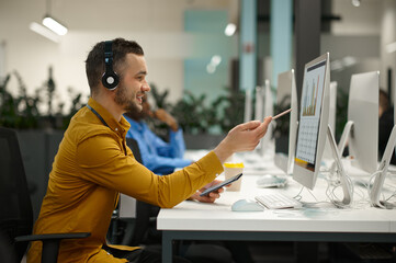 Male manager in headphones, workplace in IT office