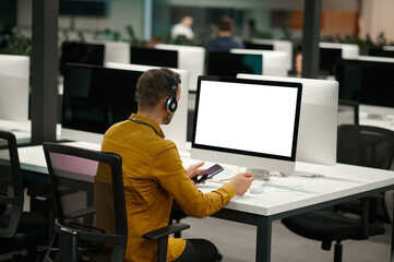 Manager in headphones works on computer, IT office