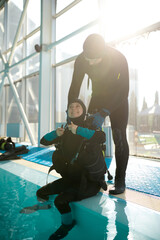 Male instructor helps woman to set up scuba gear