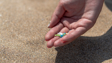 Side view of a hand holding microplastics. Non-recyclable materials. Selective focus of microplastics. Global warming and climate change concept. Selective focus with shallow depth of field         