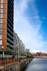 A view of buildings on the water on a sunny day over Salford Quays, Manchester, England. The image has copy space.