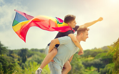 Happy young men, gay family with flying LGBT rainbow flag having fun outdoors. Joyful gay couple...