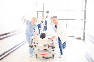 Obraz premium Doctors rushing patient on gurney in hospital corridor