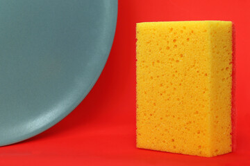 A yellow sponge and a gray plate on a red background
