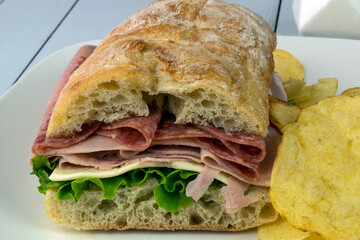 ham and salami sandwich with potato chips