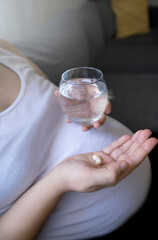 pregnant woman hand preparing to drink medicine