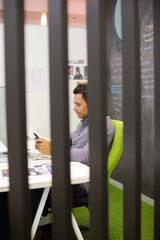 Businessman using cell phone at desk in office