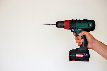 Hand with cordless screwdriver and drill isolated on white background. Twists screws into the board.