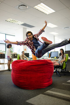 Businessman Jumping Into Beanbag Chair In Office