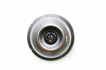 A close up image of the key hole on a black door knob with a white background. 