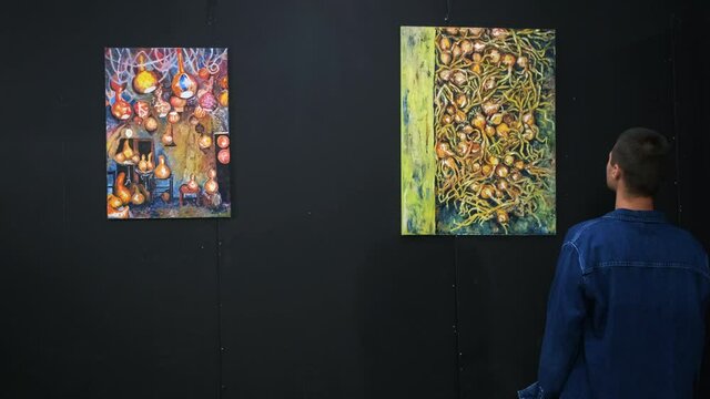young man is enjoying modern art work of talented artist in gallery