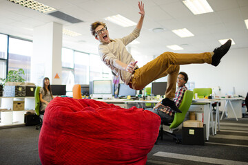Businessman jumping into beanbag chair in office