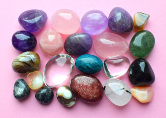 Gems of various colors. Amethyst, rose quartz, agate, apatite, aventurine, olivine, turquoise, aquamarine  and rock crystal on pink background