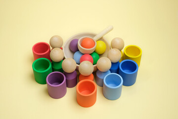 Children's wooden toy sorter for learning colors by a baby. Educational children's games. Cups and a spoon for sorting colored balls. A new modern educational toy.