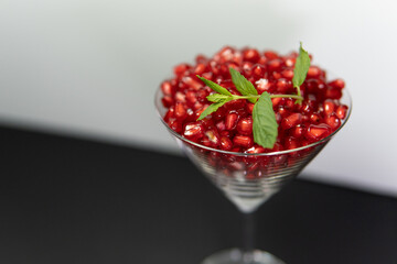 Healthy pomegranate seeds in cocktail glass with mint