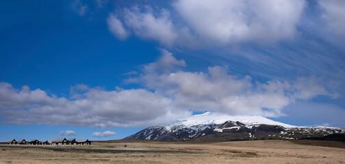 Typical wooden log houses in the barren and arid landscape near the mountain Snæfellsjökull and national park in Iceland