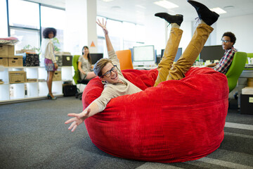 Businessman jumping into beanbag chair in office