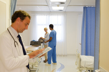 Fototapeta premium Doctor reading clipboard in hospital room
