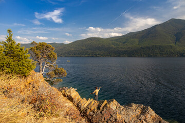 Man fly-fishing at Lake McDonald at Glacier National Park with mountain range background
