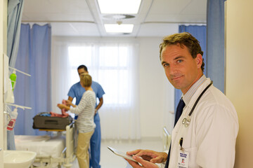 Doctor reading clipboard in hospital room