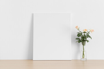 White canvas mockup with a bouquet of a pink roses on the wooden table.