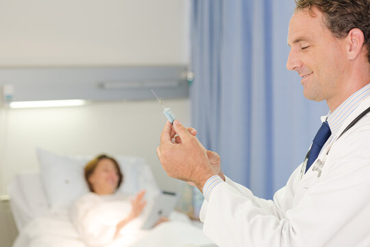 Doctor checking syringe in hospital room