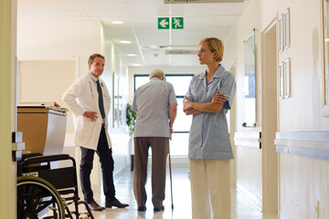 Doctor and nurse standing with patient in hospital hallway