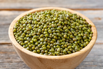 Green mung beans in a bowl on a gray wooden table. Legume plant for a healthy diet closeup