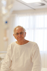 Older patient wearing gown in hospital room