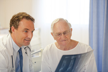 Obraz premium Doctor showing x-rays to older patient in hospital room