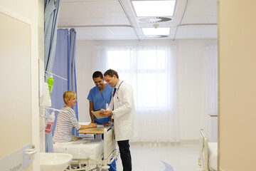 Doctor and nurse talking to patient in hospital room