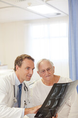Obraz premium Doctor showing x-rays to older patient in hospital room