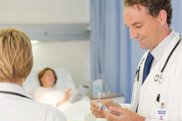 Obraz premium Doctor checking syringe in hospital room